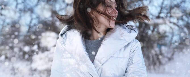 Femme avec un manteau blanc en hiver, les cheveux au vent