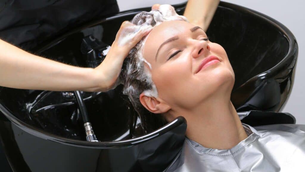 Une femme se fait masser le crâne par sa coiffeuse