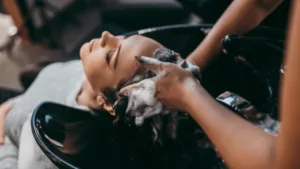 Une cliente qui se fait laver les cheveux par une coiffeuse