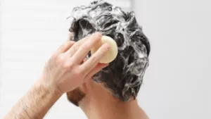 un homme qui se lave les cheveux avec un shampoing solide 