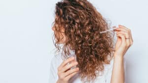 Femme se mettant un sérum dans les cheveux