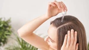 Une femme met un sérum sur ses cheveux
