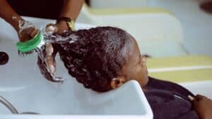 Une personne aux cheveux afro fait un shampoing dans un salon de coiffure