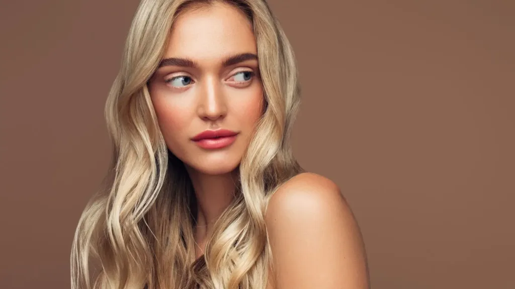 Image d'une femme qui pose sur fond marron pour montrer son babylight blond