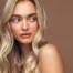 Image d'une femme qui pose sur fond marron pour montrer son babylight blond