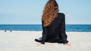 Une femme aux cheveux bouclés assise sur la plage