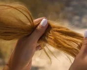 Une femme qui tient ses cheveux abimés en main