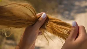 Une femme qui tient ses cheveux abimés en main