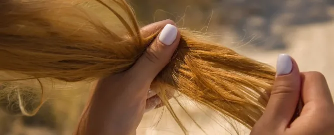 Une femme qui tient ses cheveux abimés en main