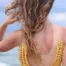 Une femme blonde tient ses cheveux abimés et secs au soleil.