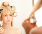 Une femme qui détache ses bigoudis pour un brushing années 70