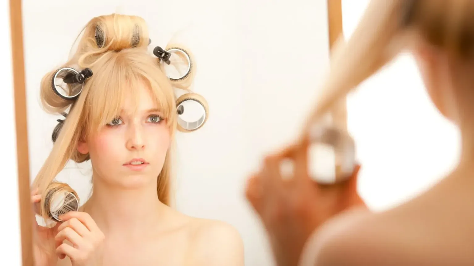 Une femme qui détache ses bigoudis pour un brushing années 70