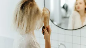 Cheveux et stress : une femme se peigne les cheveux devant le mirroir