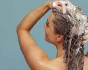 Une femme se lave les cheveux avec du shampoing après-soleil bio
