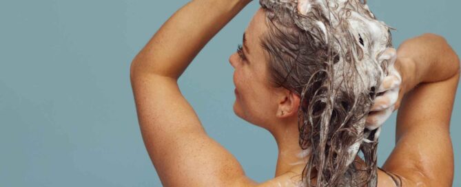 Une femme se lave les cheveux avec du shampoing après-soleil bio