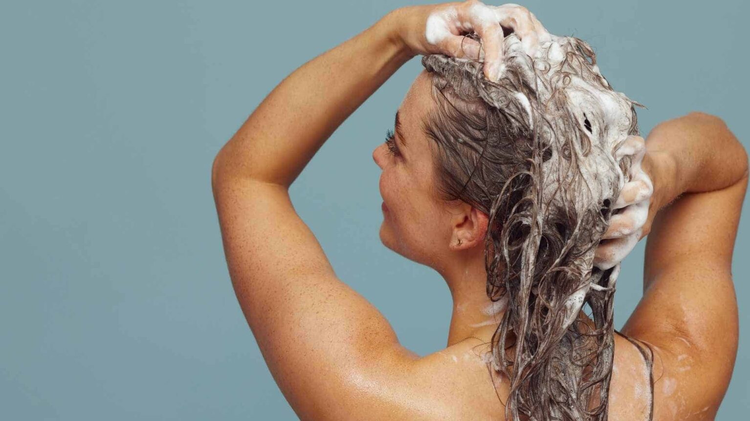Une femme se lave les cheveux avec du shampoing après-soleil bio