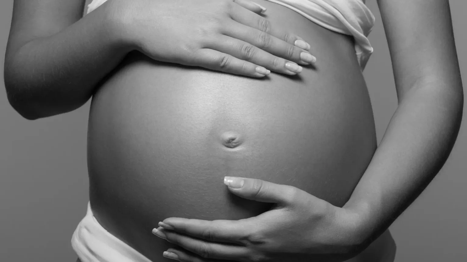 image en noir et blanc qui montre le ventre d'une femme enceinte
