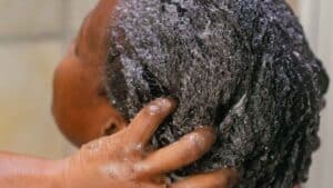 Une femme aux cheveux crépus se lave les cheveux